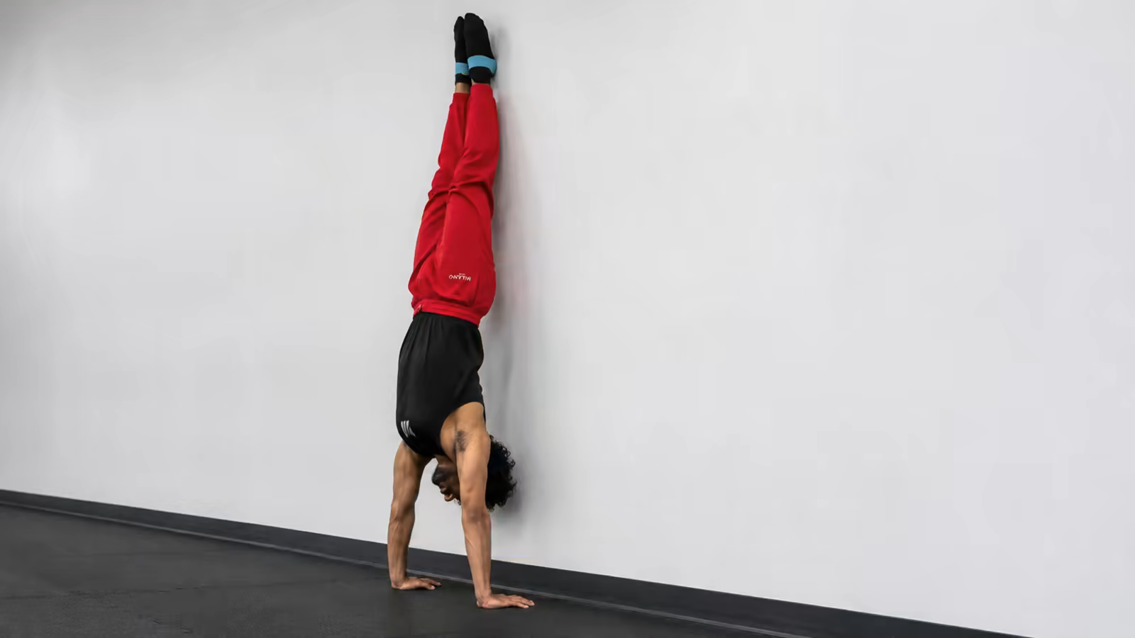 Wall handstand work isn't a crutch — it's where your nervous system learns what straight actually feels like.